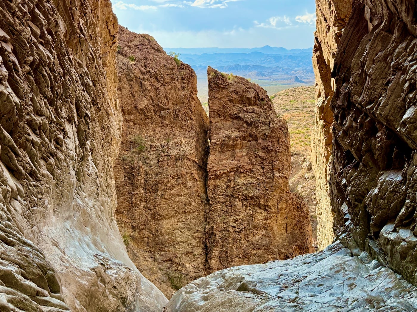 View through the Window pour-off — the entire Chisos drainage funneling through a flash-flood-sculpted notch and out toward the open desert, Big Bend National Park