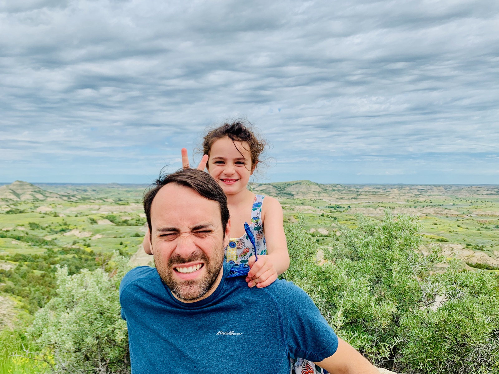 A daughter giving Sprinterdad bunny ears above the colorful badlands