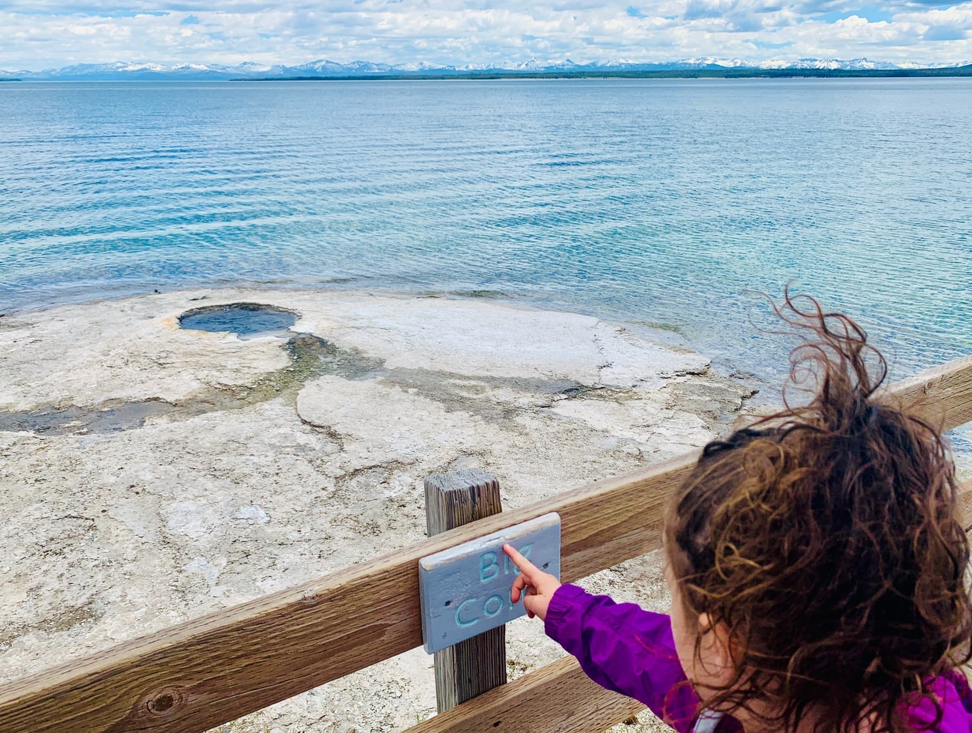 A daughter pointing out the Big Cone along the edge of Yellowstone Lake