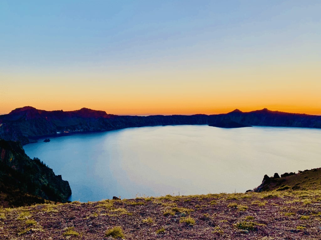 Crater Lake ethereal deep blue waters with a rainbow sunset with Wizard Island and Phantom Ship full panoramic view