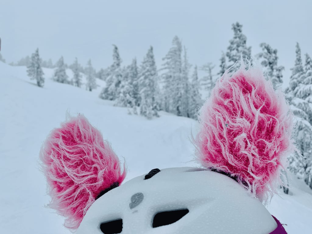 Mt Bachelor Valentines Storm Pink Puffs on younger kid ski helmet in Bend with hoarfrost conifers and white storm sky in the background