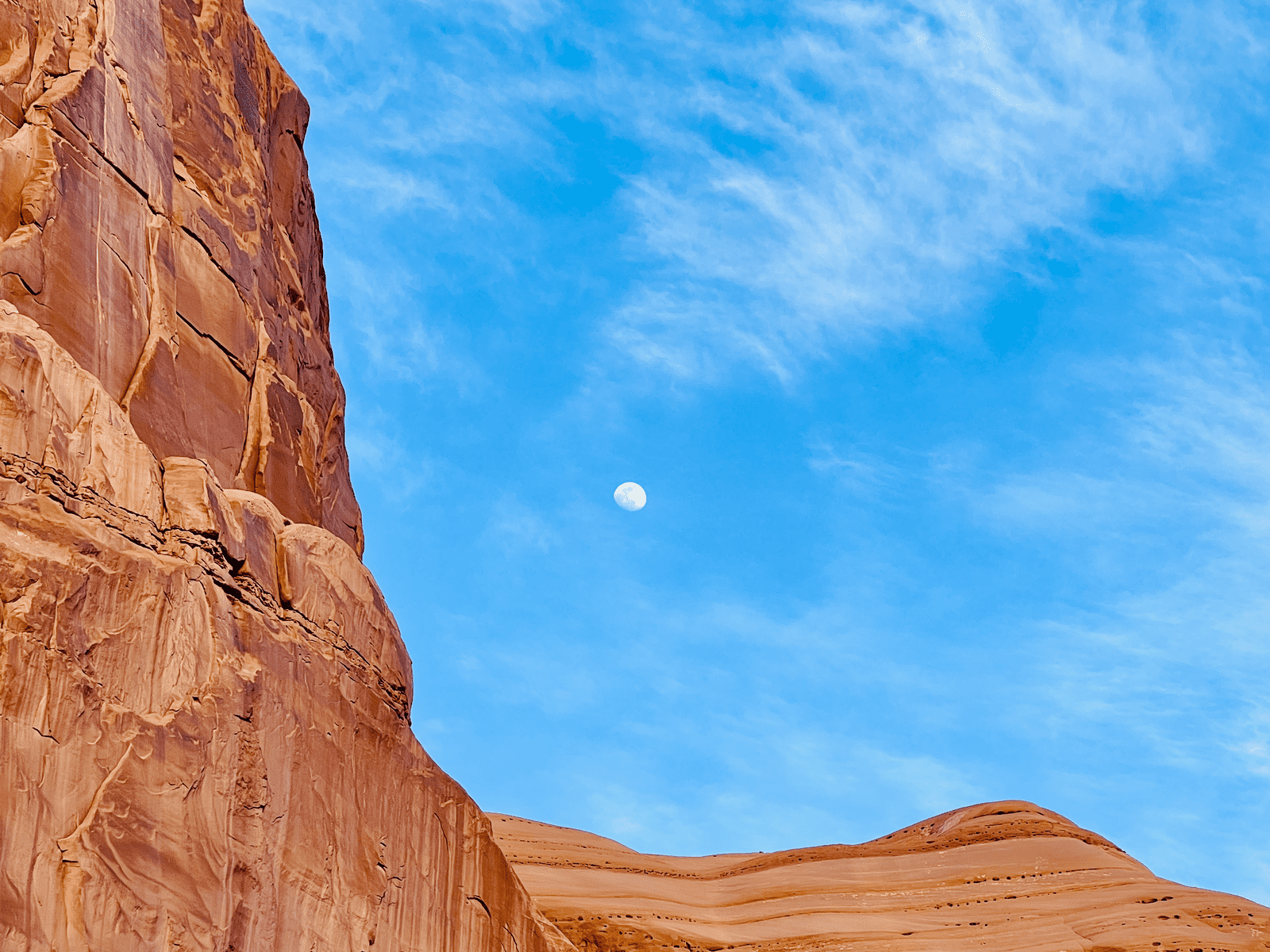 Wonder Rocks and bright waxing gibbous Moon at Arches National Park with blue dusk skies in the background