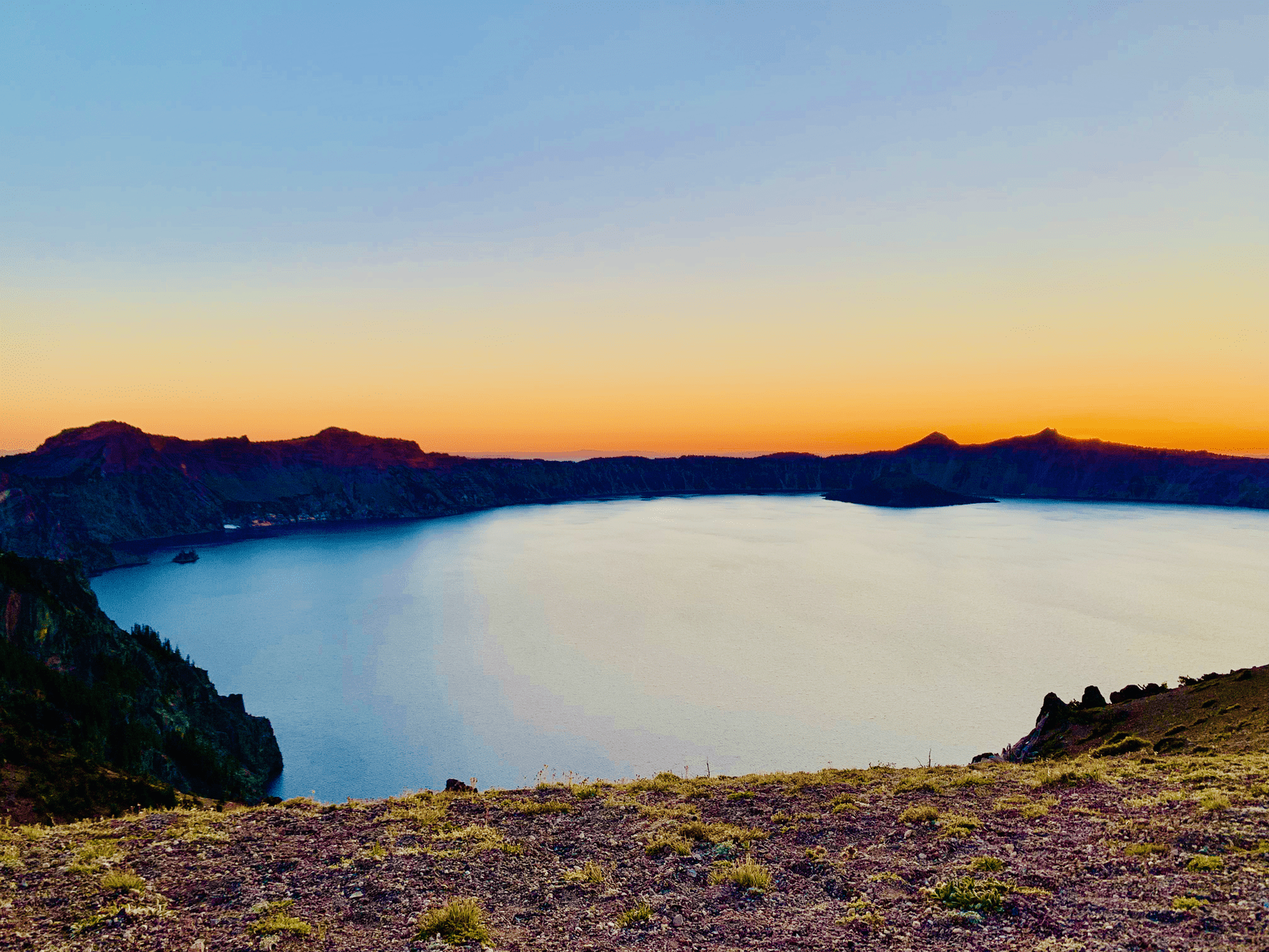 Crater Lake ethereal deep blue waters with a rainbow sunset with Wizard Island and Phantom Ship full panoramic view